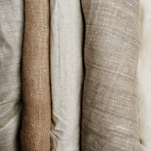 Natural fabrics from organic colors of flax and cotton in rolls, homespun textile handmade. Burlap and canvas for eco, rustic, boho, hygge decor